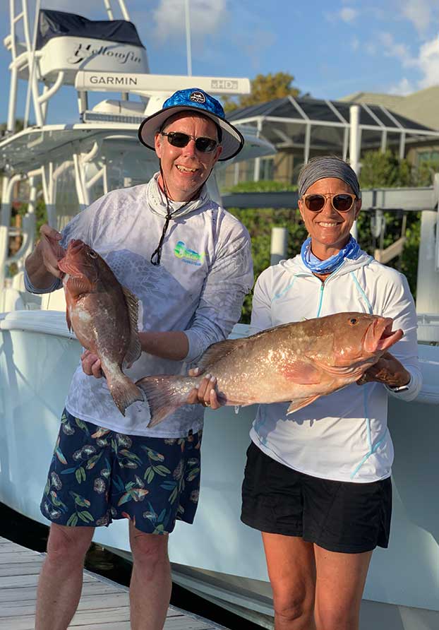 Happy couple with large grouper fish caught during an off-shore fishing charter with Dahl-Fins Charters